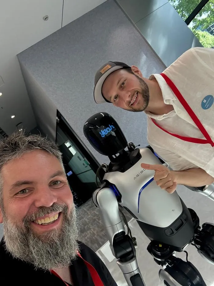 Zwei myblock-Gründer mit einem humanoiden Roboter auf einer Technologiemesse.